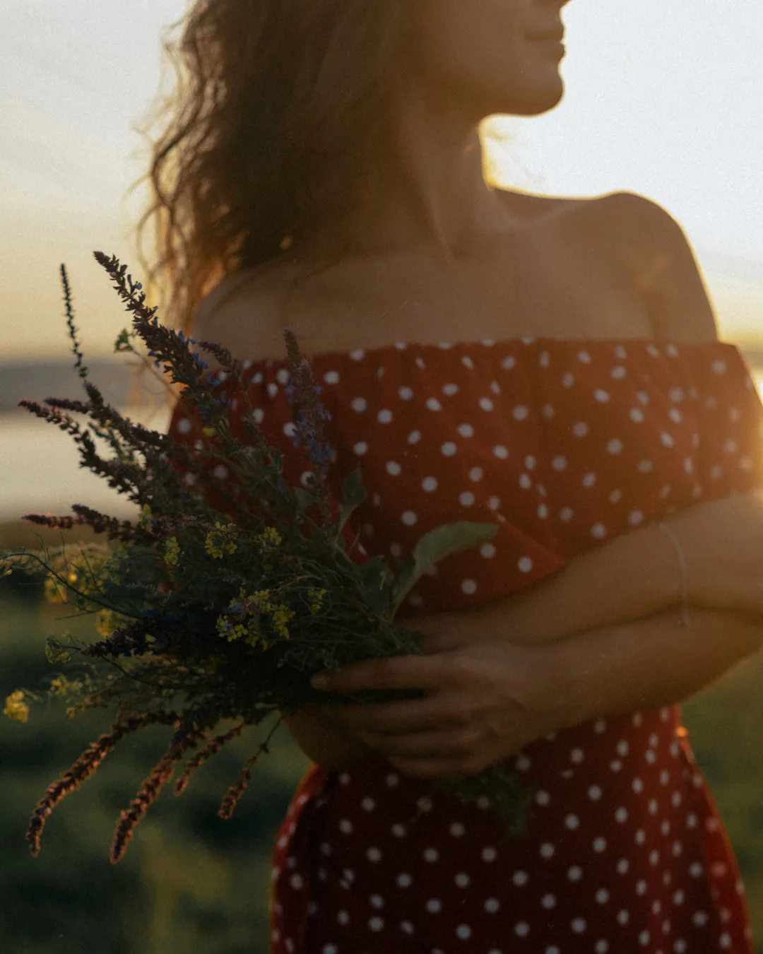 Woman holding wildflowers in warm sunlight