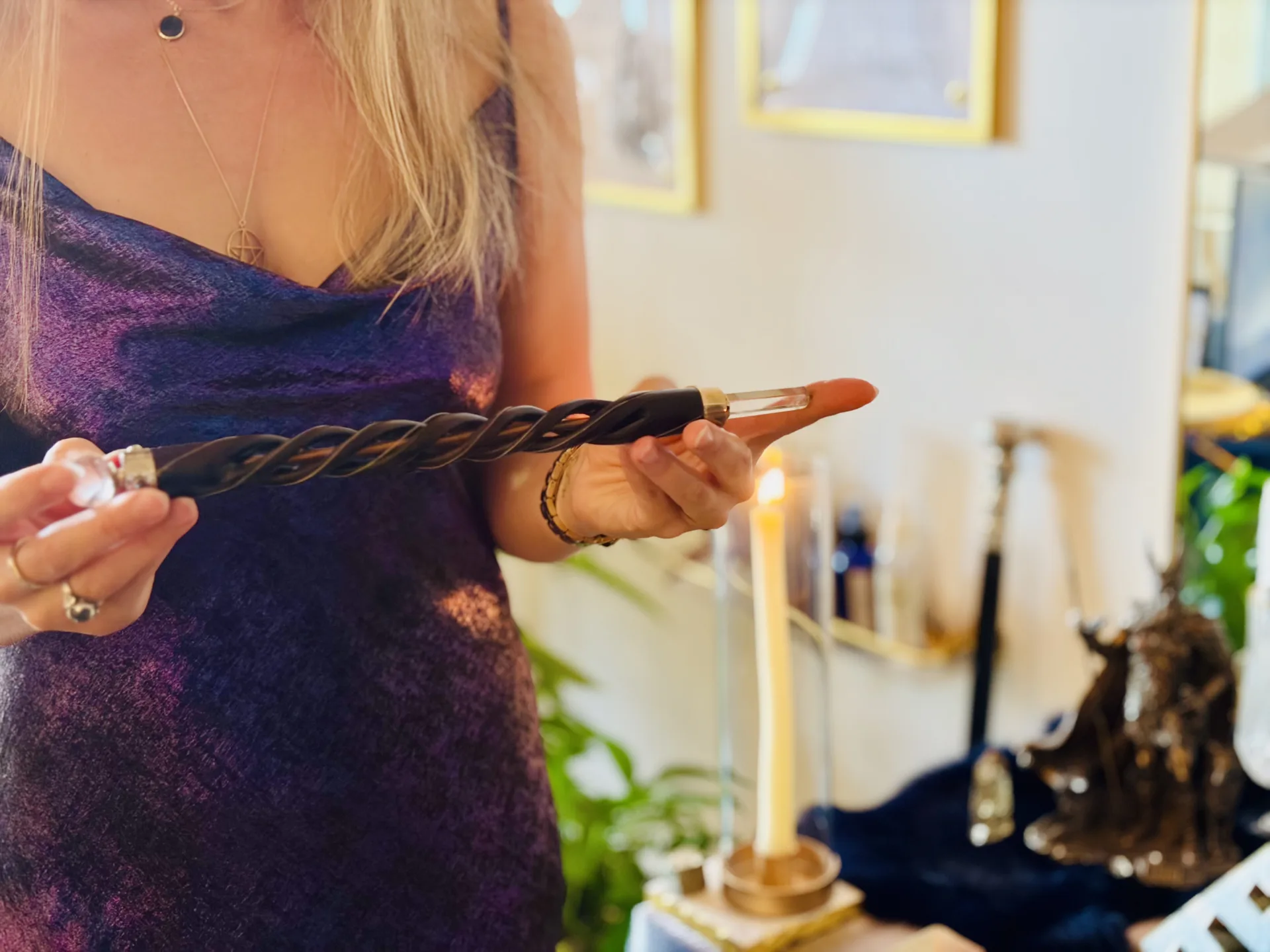 Laura holding a ritual wand with crystal tip, sacred candles burning