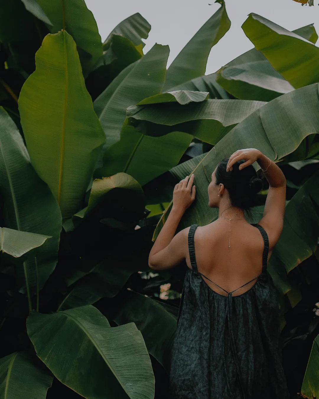 Woman surrounded by lush tropical leaves in a thoughtfully designed space
