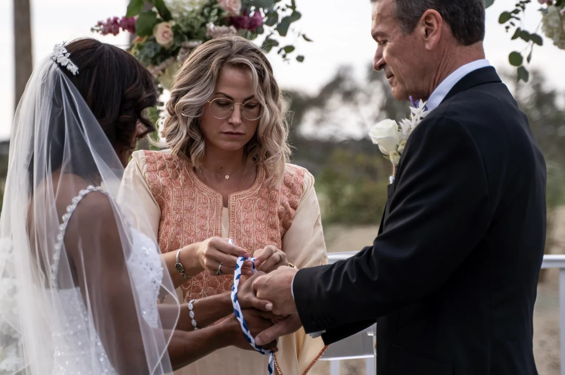 Wedding officiant guiding a handfasting ritual during an outdoor ceremony